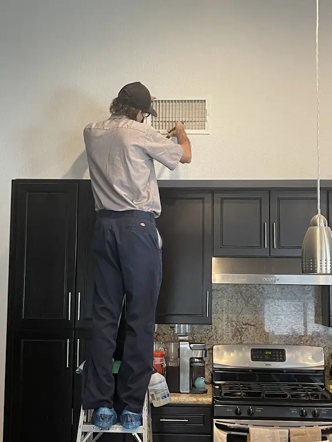 Technician inspecting an air vent during HVAC service in Birmingham